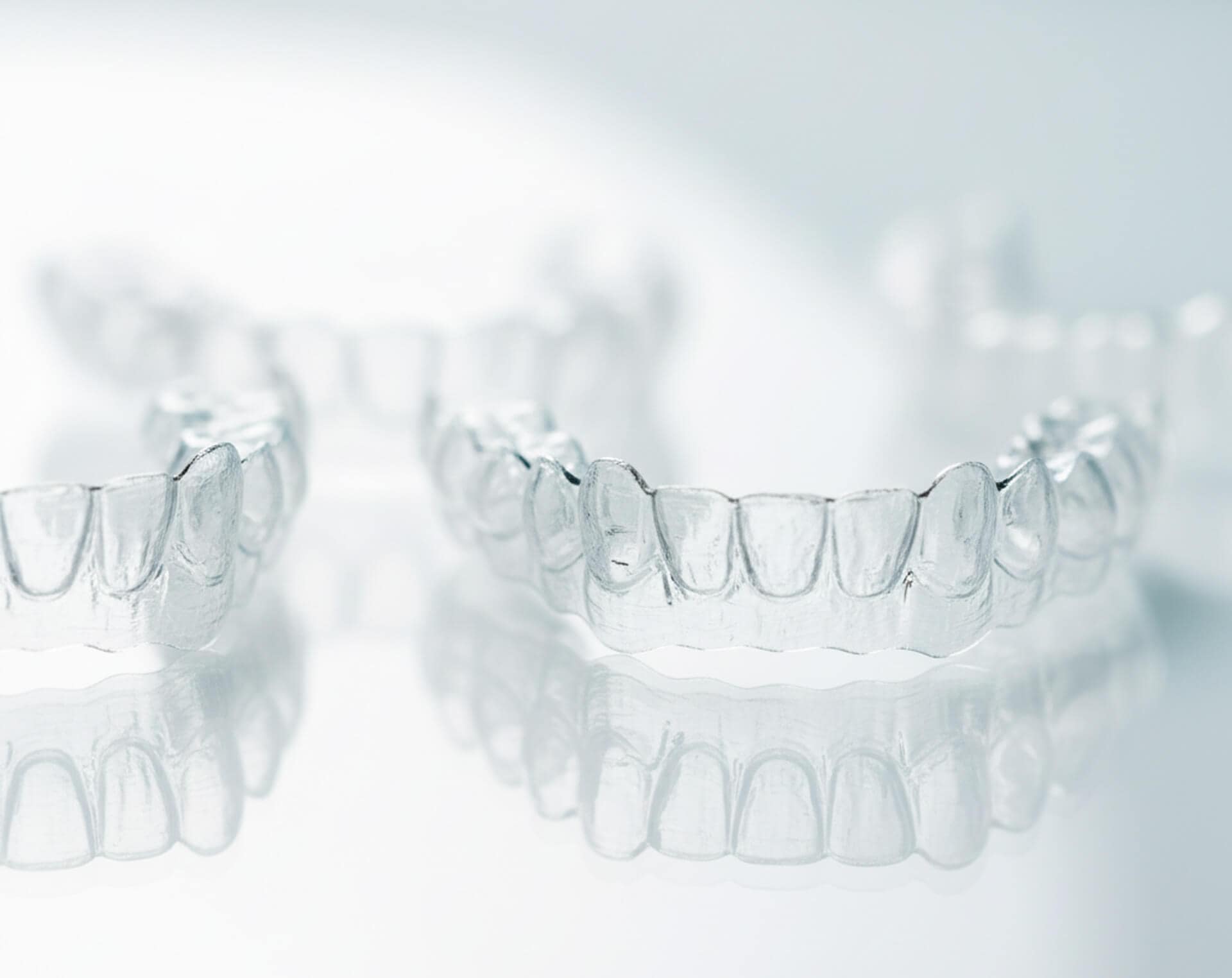 Clear Invisalign aligners reflecting light, showcasing a comfortable and discreet orthodontic solution for teeth straightening.