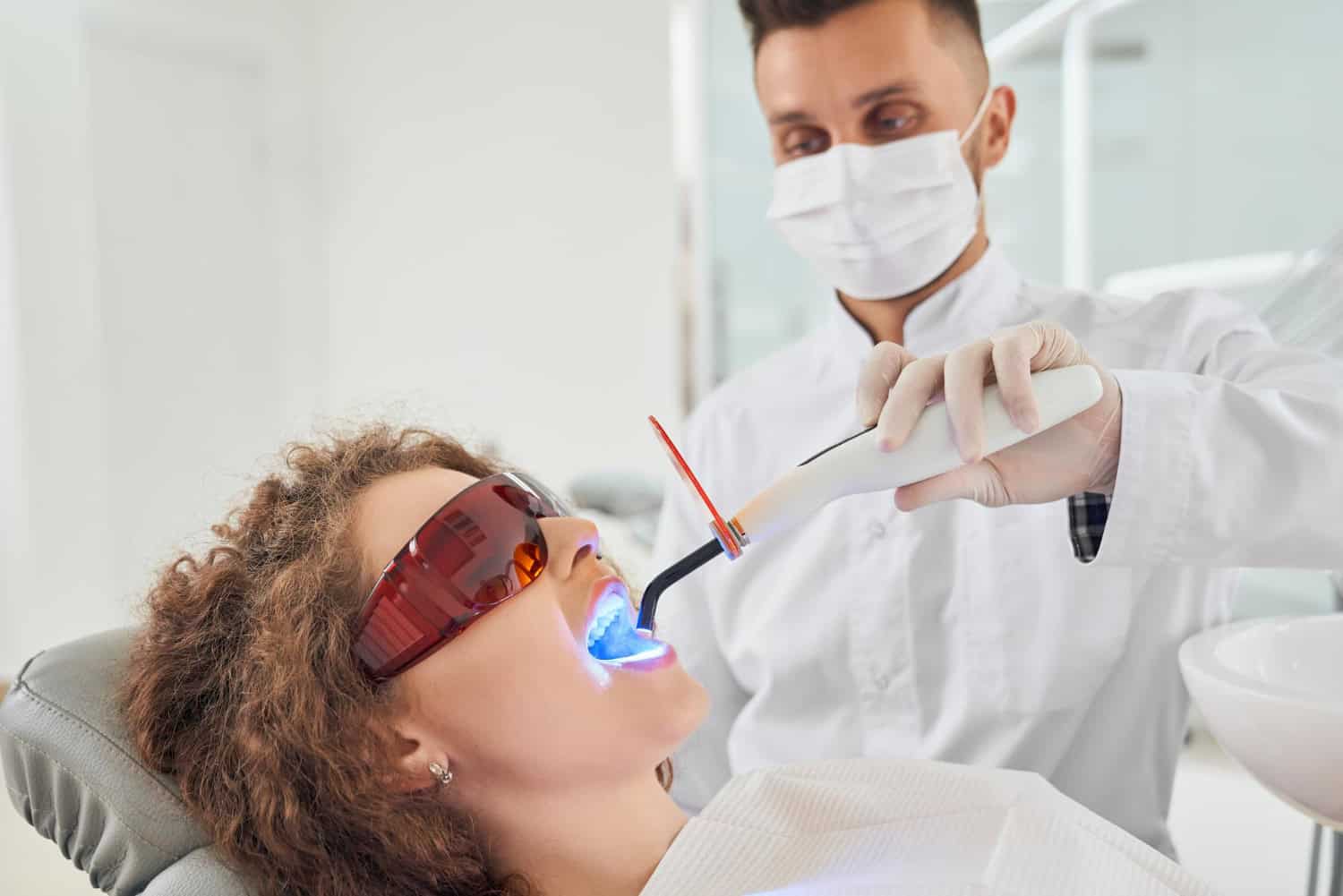 Patient receiving professional in-office teeth whitening treatment with LED whitening light at a dental clinic in Westford, MA.