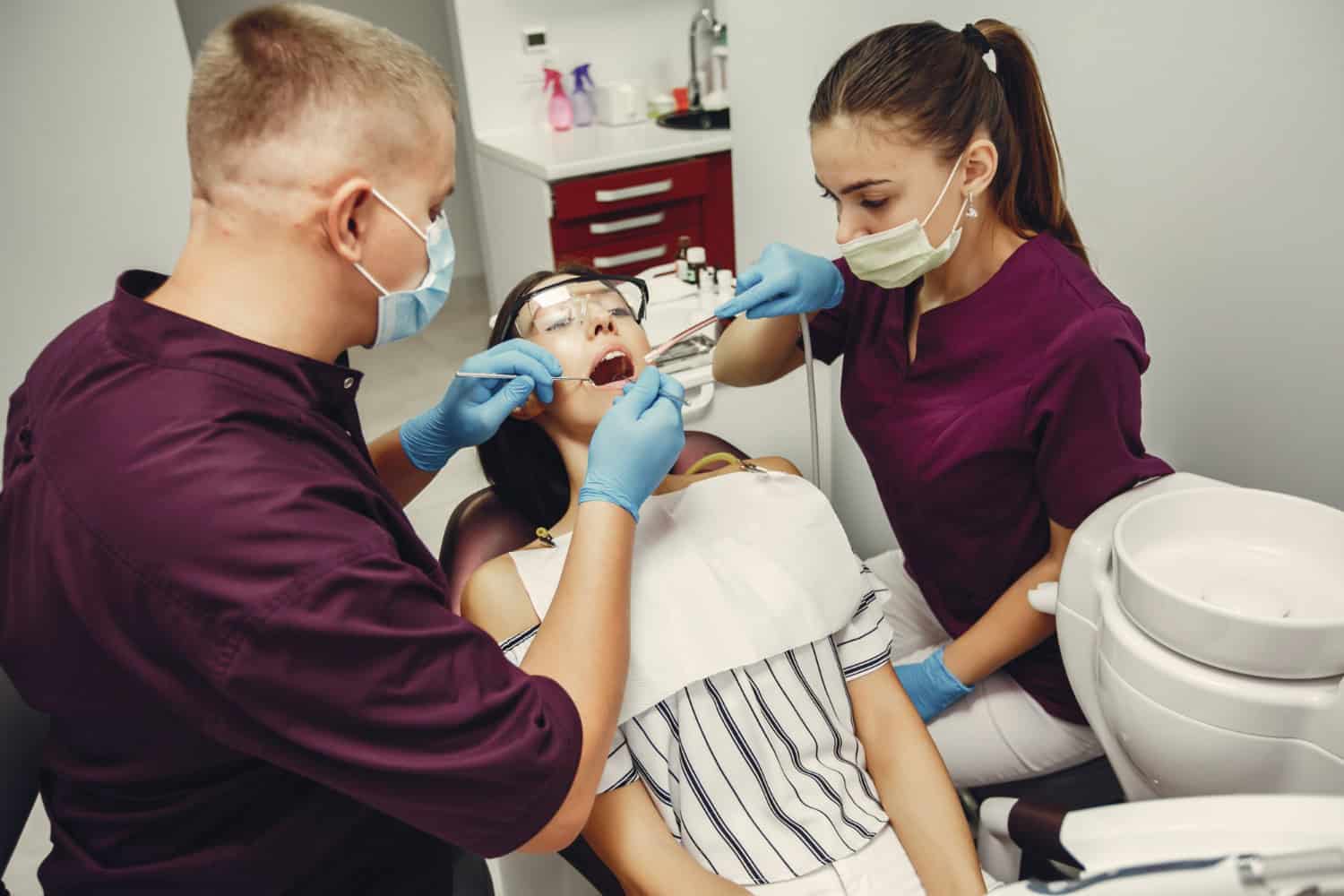 Dentist and dental assistant examining a patient during a dental treatment procedure.