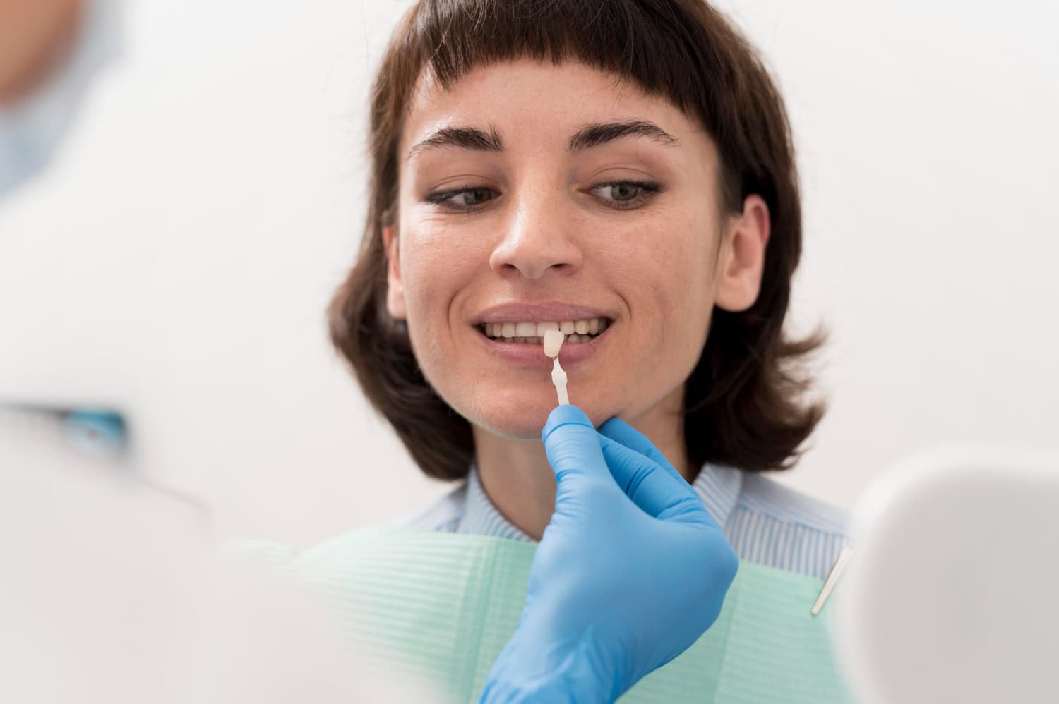 Dentist checks a patient's tooth shade during a porcelain crown fitting for a natural-looking smile.