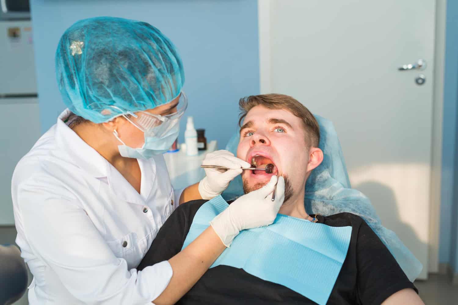 Dentist examining a patient during a dental crown procedure and oral examination.