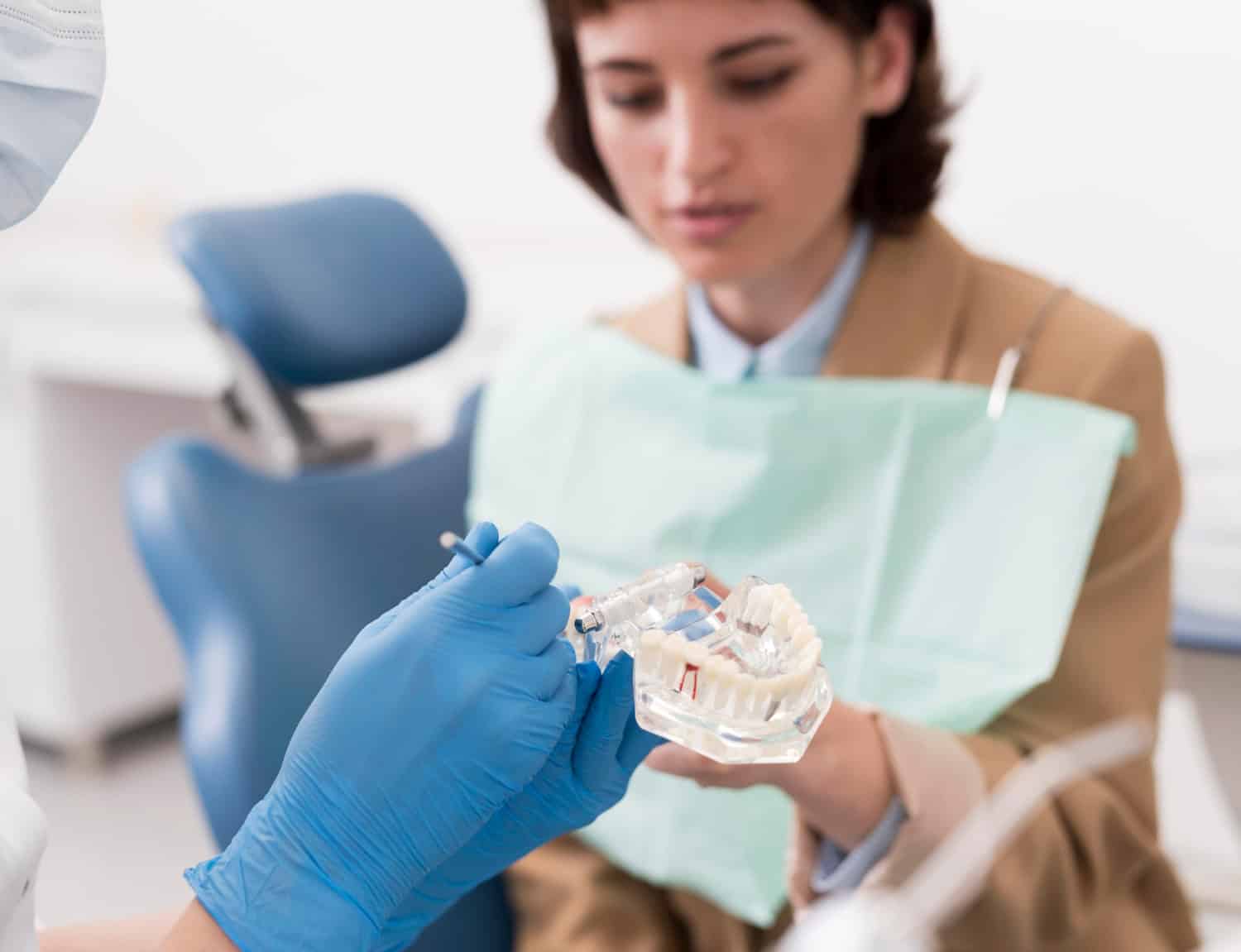 Dentist explaining clear aligner treatment using a dental model during a patient consultation.