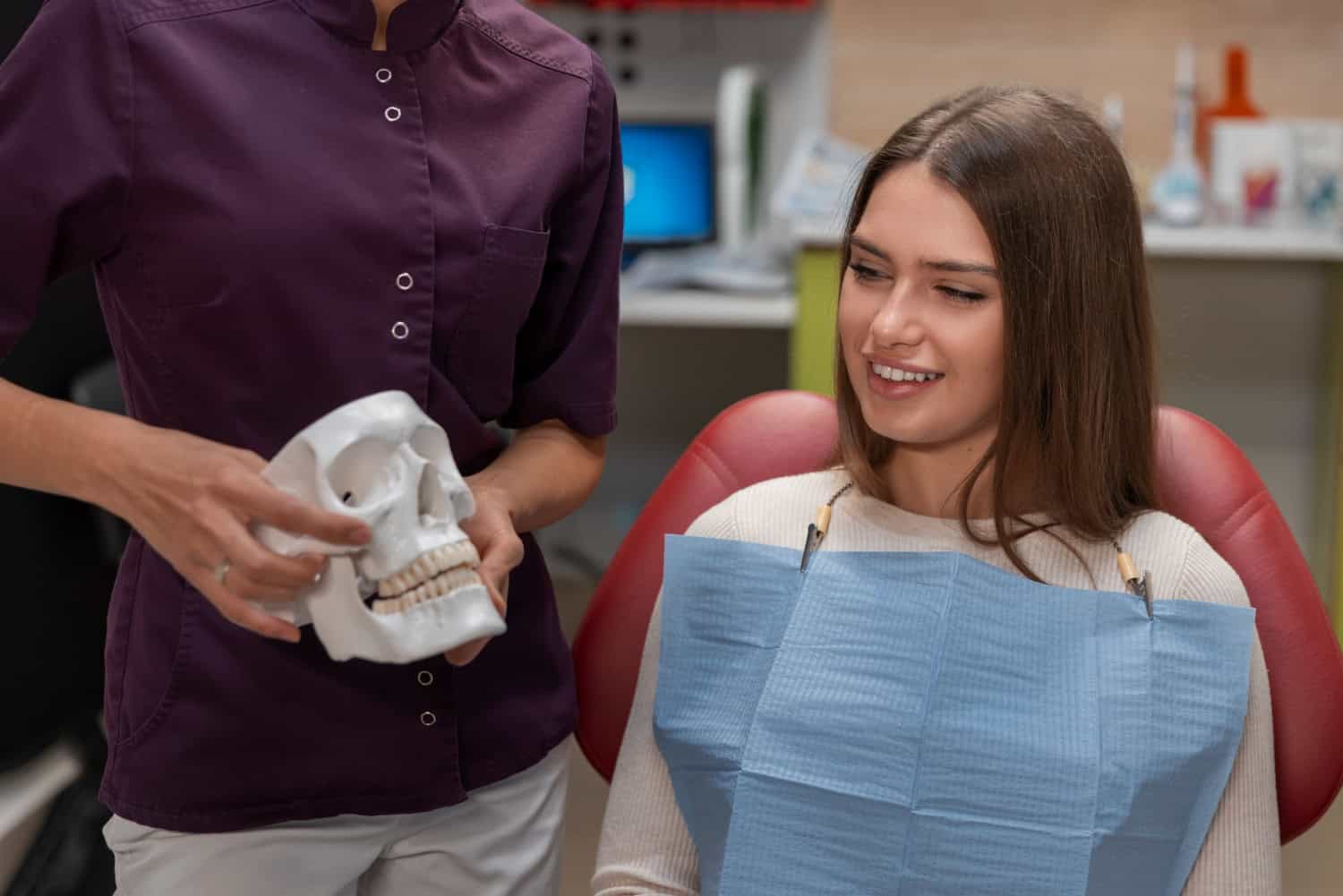 Dentist explaining jaw and bite alignment to a patient using a dental skull model during a consultation.