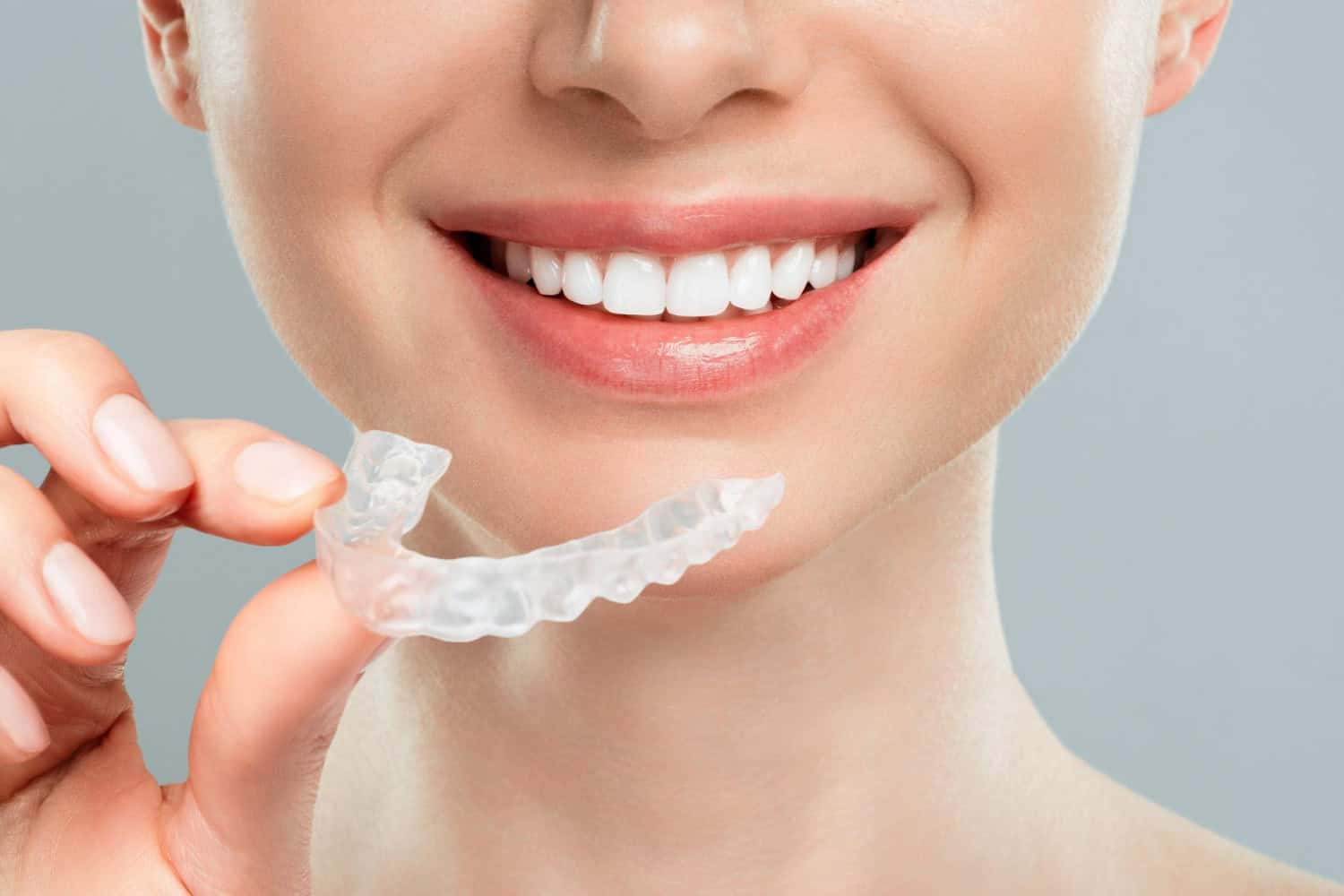 Clear aligner being removed to reveal a straighter, brighter smile during discreet orthodontic treatment.