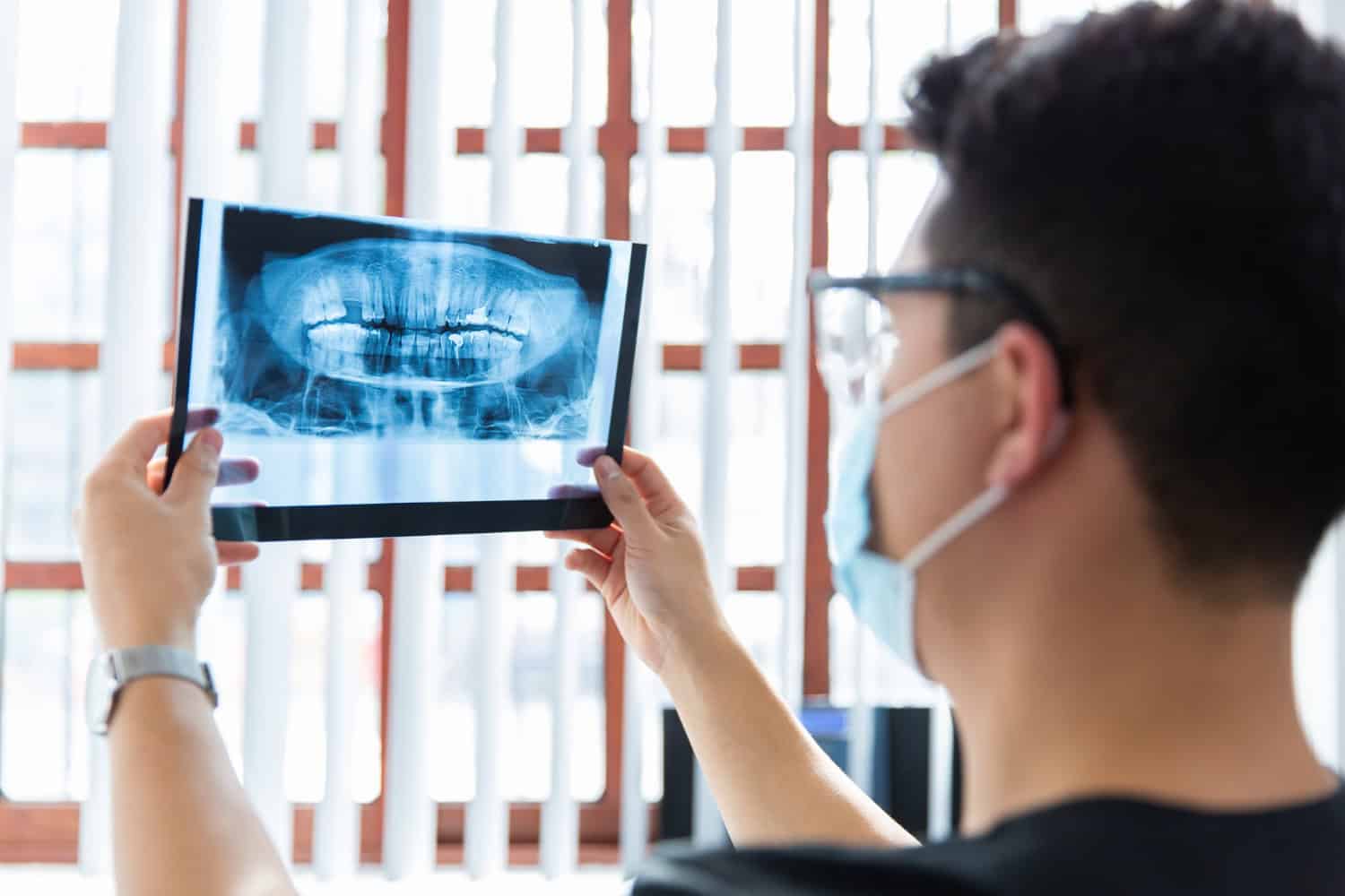 Dentist reviewing a dental X-ray to explain AI dental diagnostics and digital imaging during a patient exam.