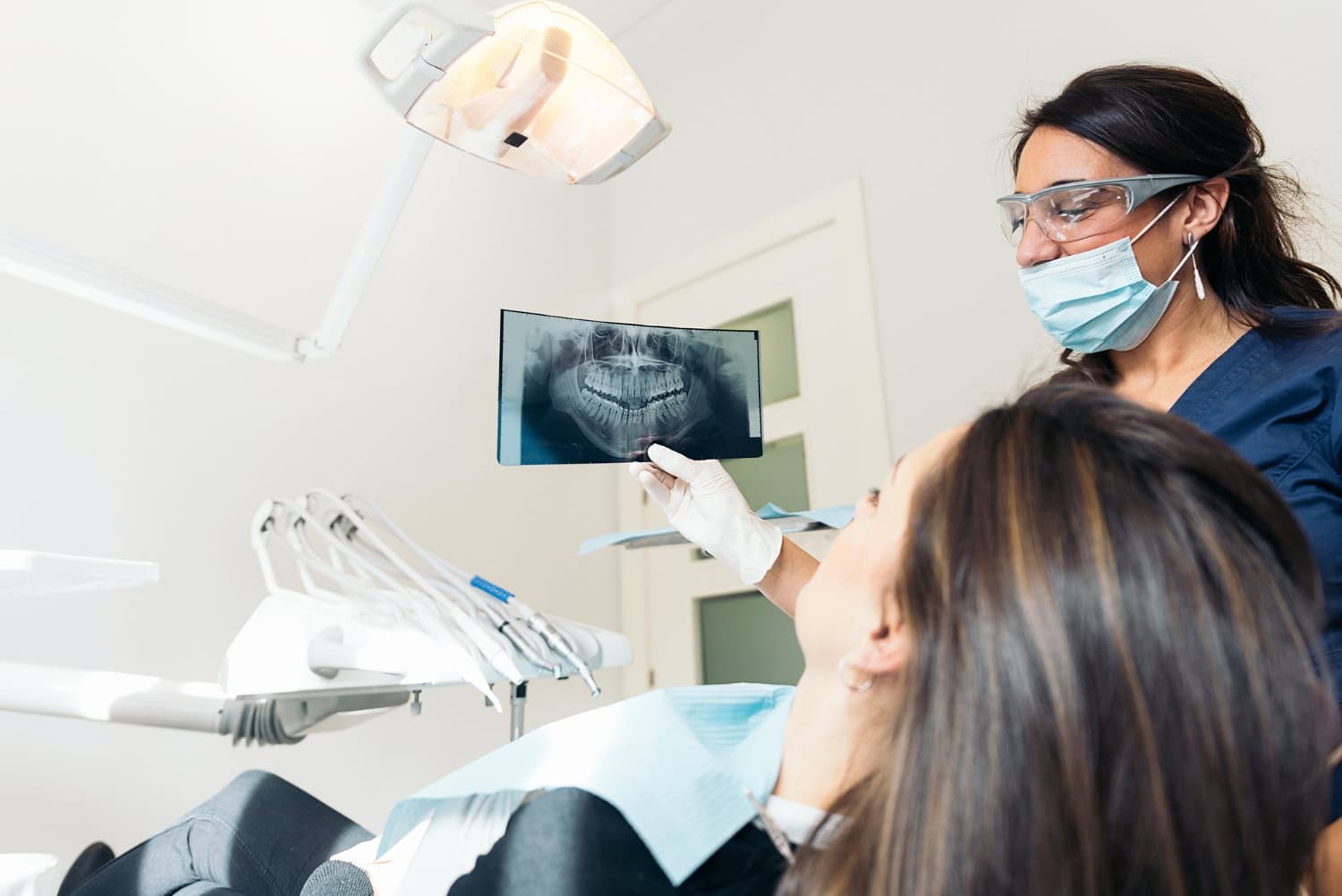 Dentist showing a patient her dental X-ray during an AI dental diagnostics consultation for early oral health assessment.