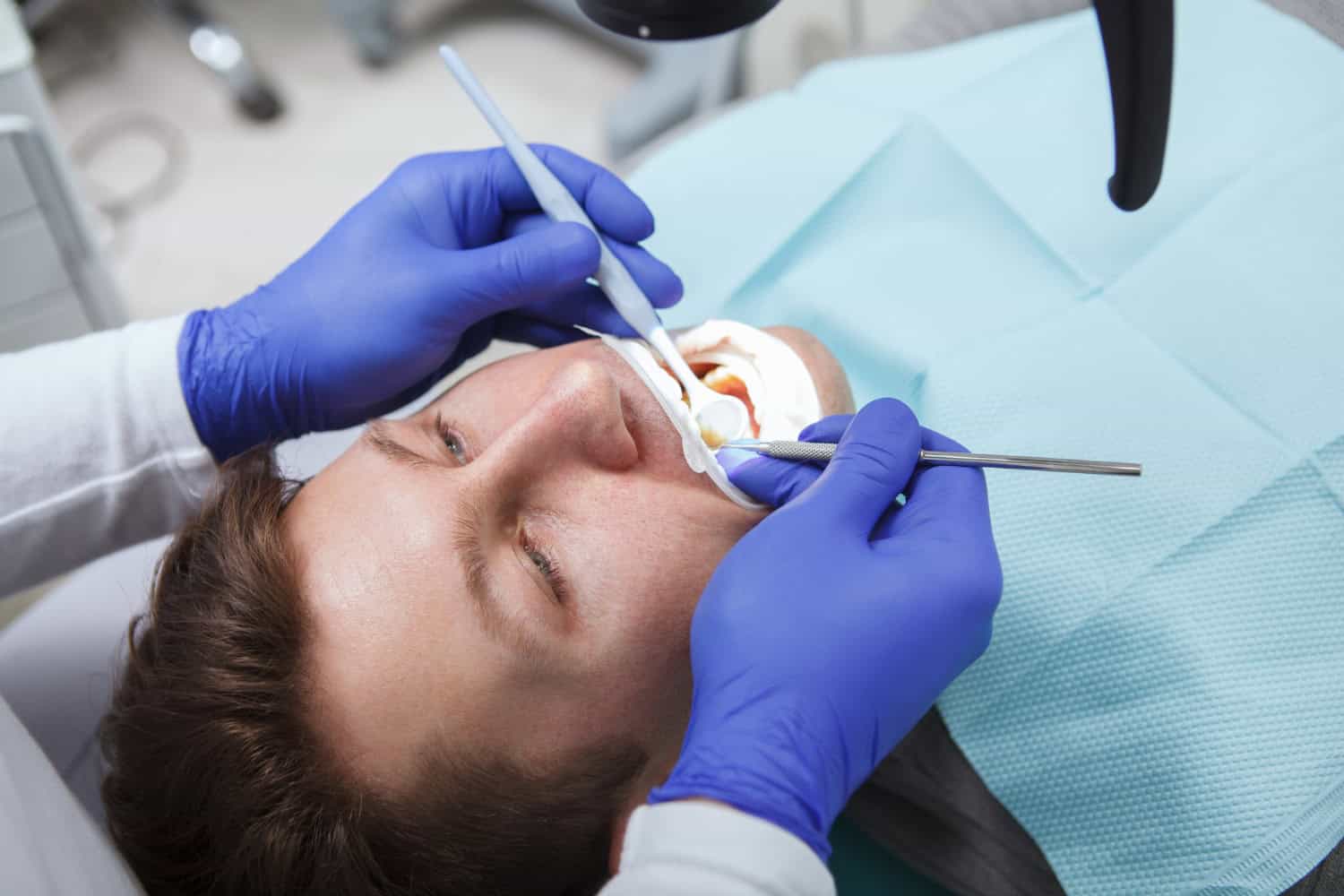 Dentist examining a patient during dental crown replacement and recementing, evaluating a loose crown and providing restorative dental care.